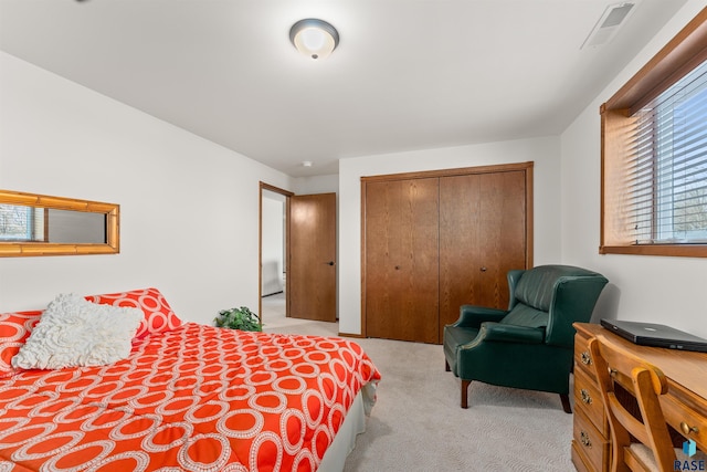 bedroom with visible vents, a closet, and light carpet