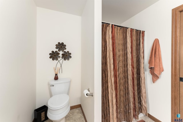 bathroom featuring a shower with curtain, toilet, baseboards, and tile patterned flooring