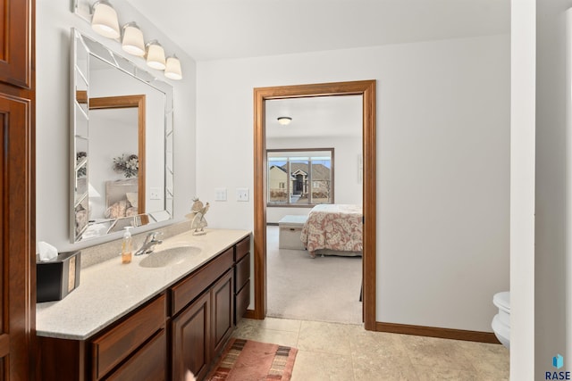 ensuite bathroom with vanity, toilet, baseboards, and connected bathroom