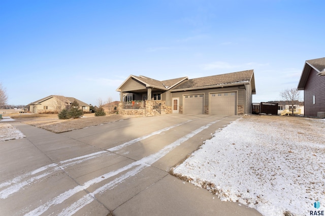 single story home with stone siding, covered porch, driveway, and an attached garage