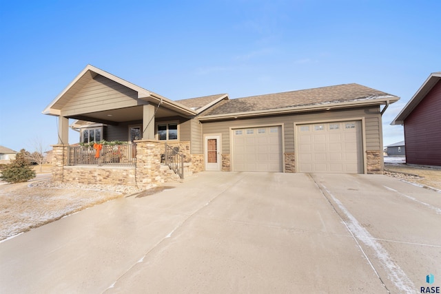 view of front of home featuring stone siding, driveway, a garage, and roof with shingles