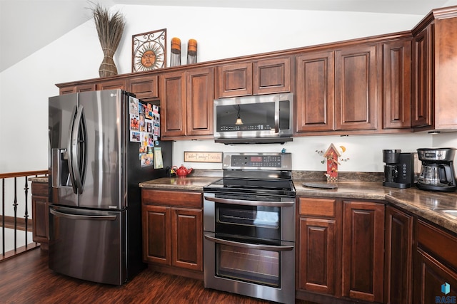 kitchen featuring dark countertops, dark wood-type flooring, appliances with stainless steel finishes, and vaulted ceiling