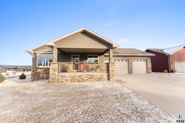 view of front of house featuring a garage, stone siding, a porch, and driveway