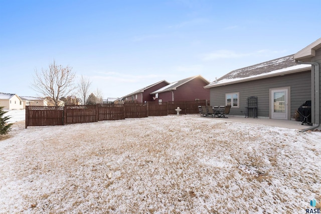 yard covered in snow with a patio and fence