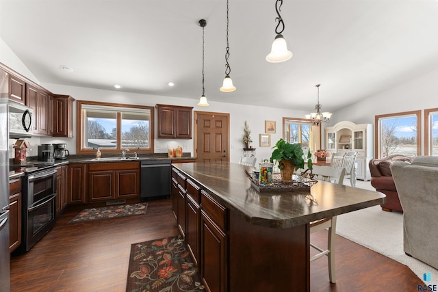 kitchen with dark countertops, dark wood-style floors, appliances with stainless steel finishes, and vaulted ceiling