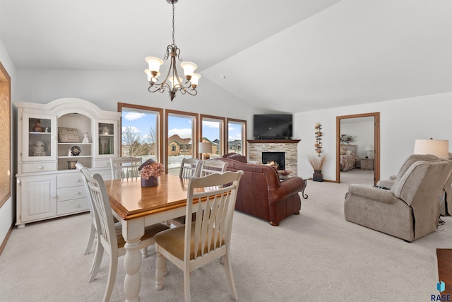 dining room featuring a stone fireplace, lofted ceiling, a notable chandelier, and light carpet