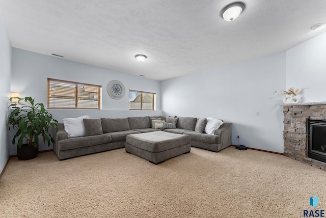 living area featuring visible vents, a textured ceiling, carpet floors, a stone fireplace, and baseboards