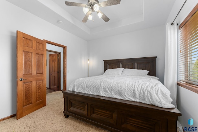 bedroom with light colored carpet, a ceiling fan, a raised ceiling, and baseboards