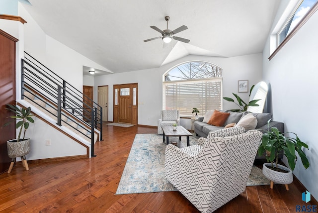 living room with stairway, a ceiling fan, baseboards, hardwood / wood-style flooring, and vaulted ceiling