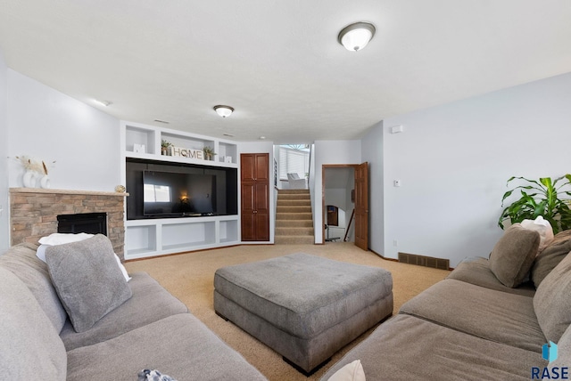 living room featuring visible vents, built in shelves, stairway, a fireplace, and light colored carpet