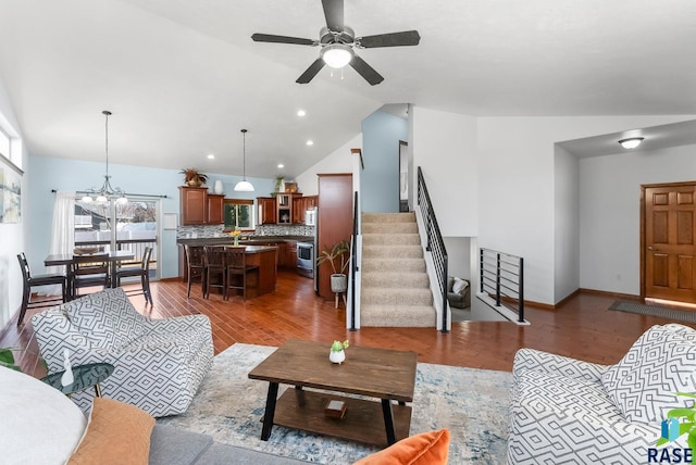 living area featuring stairway, ceiling fan with notable chandelier, lofted ceiling, and wood finished floors