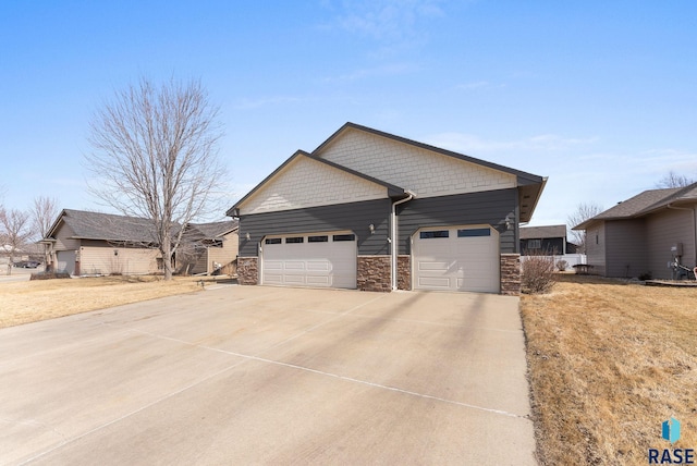 view of property exterior featuring a garage, stone siding, and driveway