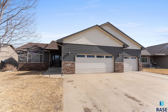 craftsman-style house featuring stone siding, driveway, and an attached garage