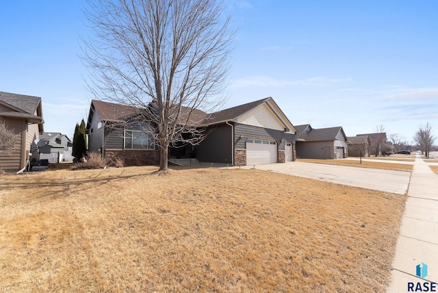 single story home with stone siding, an attached garage, and concrete driveway