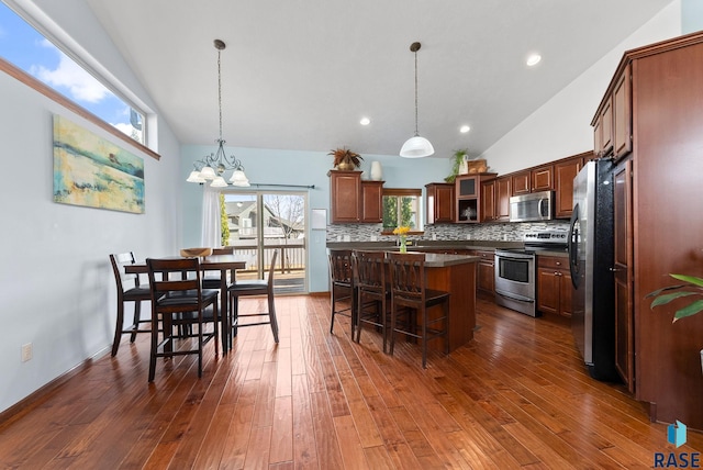 kitchen with dark countertops, a kitchen island, a breakfast bar area, decorative backsplash, and stainless steel appliances