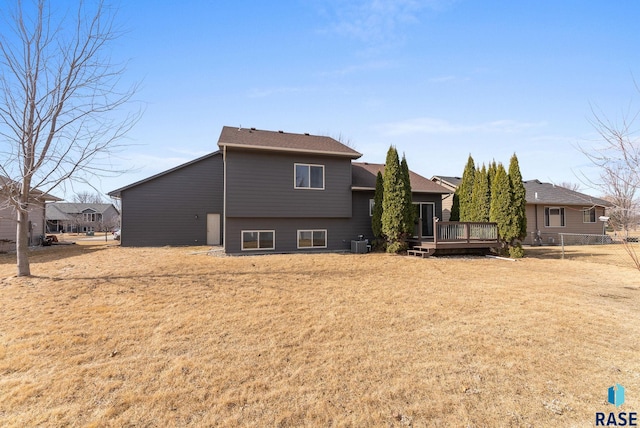 back of house featuring a lawn, a deck, central AC, fence, and a shingled roof