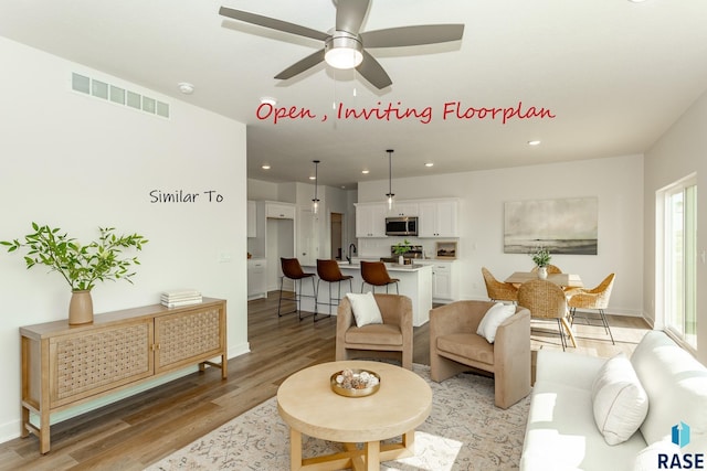 living area with visible vents, light wood-style flooring, a ceiling fan, recessed lighting, and baseboards