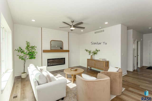 living area with a ceiling fan, wood finished floors, and visible vents