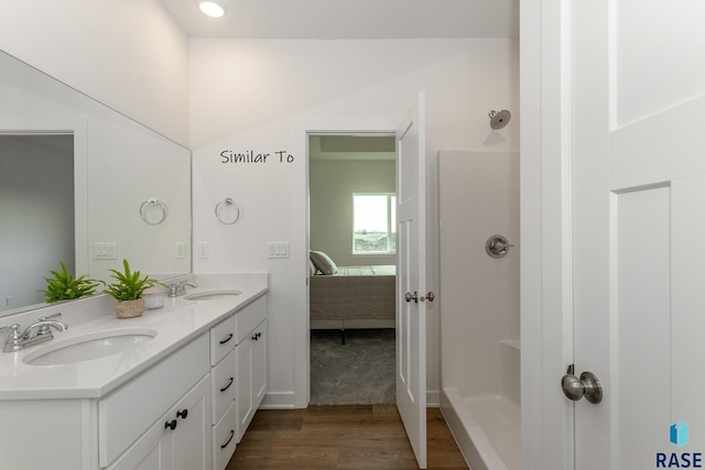 bathroom with a sink, double vanity, wood finished floors, and ensuite bathroom