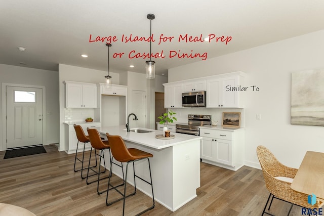 kitchen featuring white cabinets, appliances with stainless steel finishes, light wood-style floors, and a sink