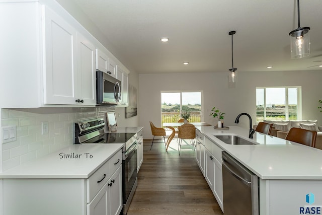 kitchen with wood finished floors, a sink, stainless steel appliances, white cabinets, and tasteful backsplash