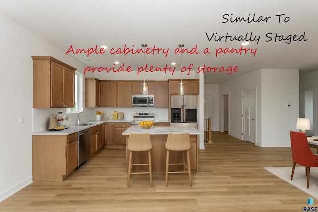 kitchen with a sink, a kitchen island, appliances with stainless steel finishes, a breakfast bar area, and light countertops