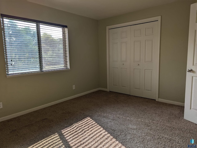 unfurnished bedroom with a closet, baseboards, and carpet flooring