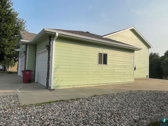 view of side of home with a garage and a shingled roof