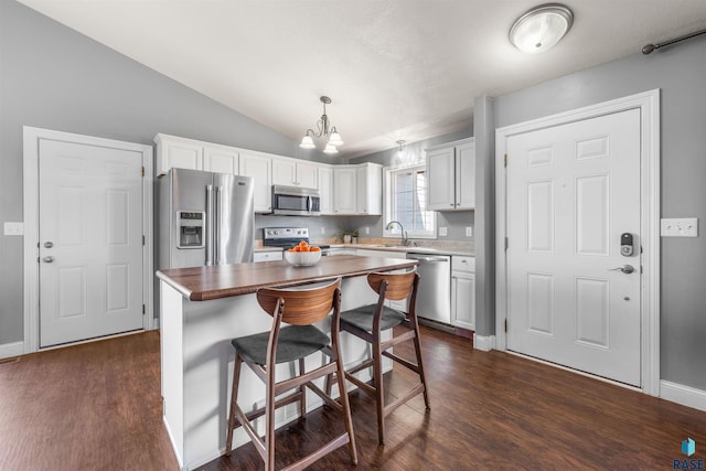 kitchen with a kitchen island, a chandelier, vaulted ceiling, appliances with stainless steel finishes, and dark wood-style flooring