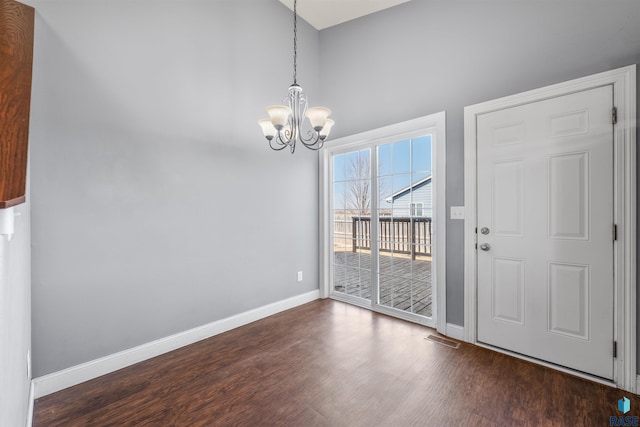 unfurnished dining area with dark wood-type flooring, a notable chandelier, baseboards, and visible vents