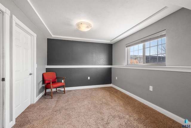 sitting room with carpet, baseboards, and a textured wall