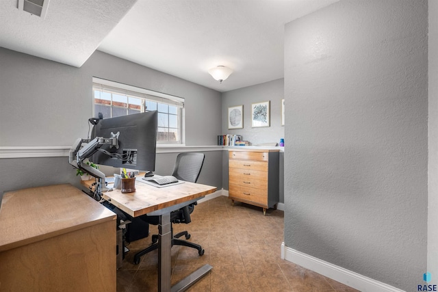 office space with visible vents, baseboards, and a textured wall