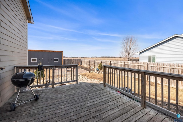 wooden deck featuring a fenced backyard and a grill