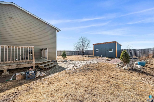 view of yard with a deck, an outbuilding, and a fenced backyard