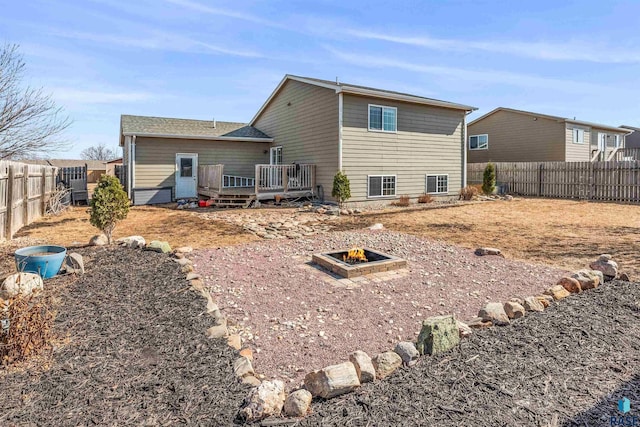 back of property featuring a deck, a fire pit, and a fenced backyard