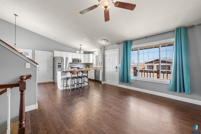 interior space featuring visible vents, a ceiling fan, a kitchen breakfast bar, stainless steel appliances, and white cabinets