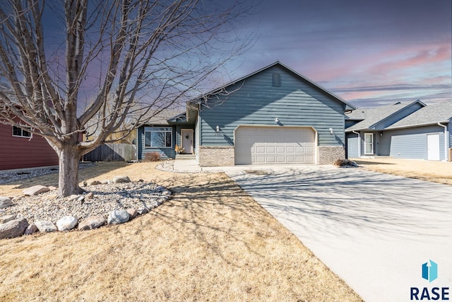 single story home with a garage, brick siding, concrete driveway, and fence