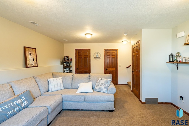 living area featuring a textured ceiling, visible vents, baseboards, and light carpet