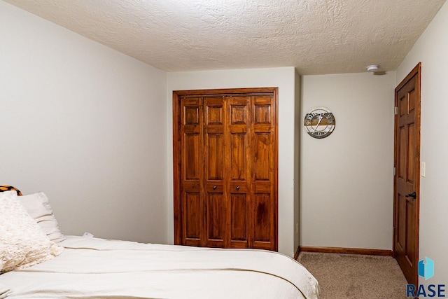 bedroom with baseboards, carpet floors, a textured ceiling, and a closet