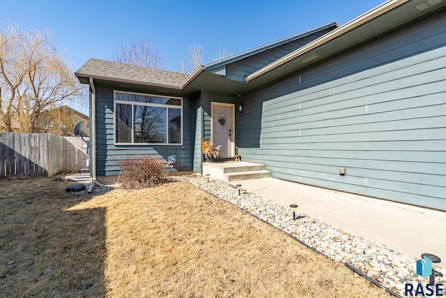 view of front of home featuring fence and roof with shingles