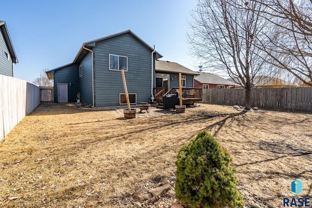 rear view of property featuring a wooden deck, a fenced backyard, and an outdoor fire pit