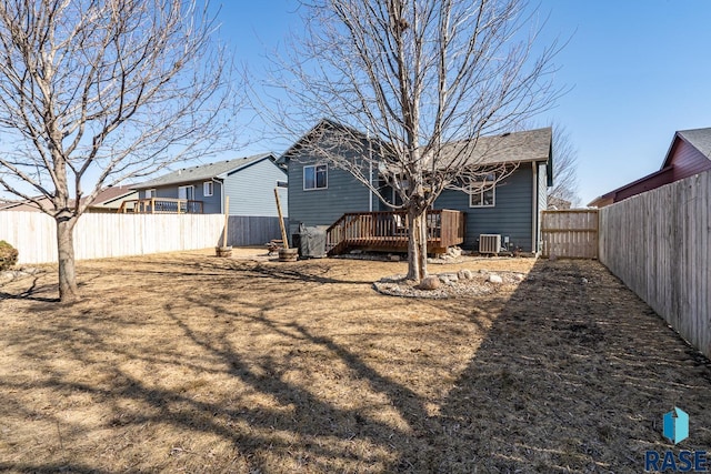 rear view of house featuring a deck, central AC unit, and a fenced backyard