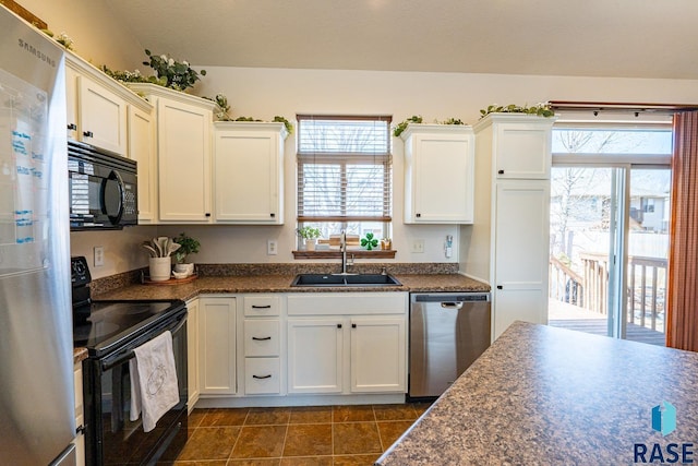 kitchen featuring black appliances, dark tile patterned floors, a sink, dark countertops, and white cabinetry