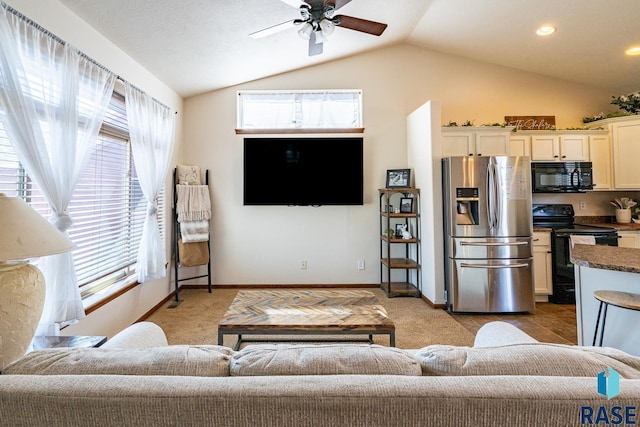 living area featuring vaulted ceiling, a ceiling fan, baseboards, and light carpet