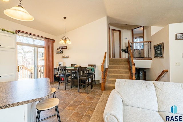 dining space featuring a chandelier, stairway, and vaulted ceiling