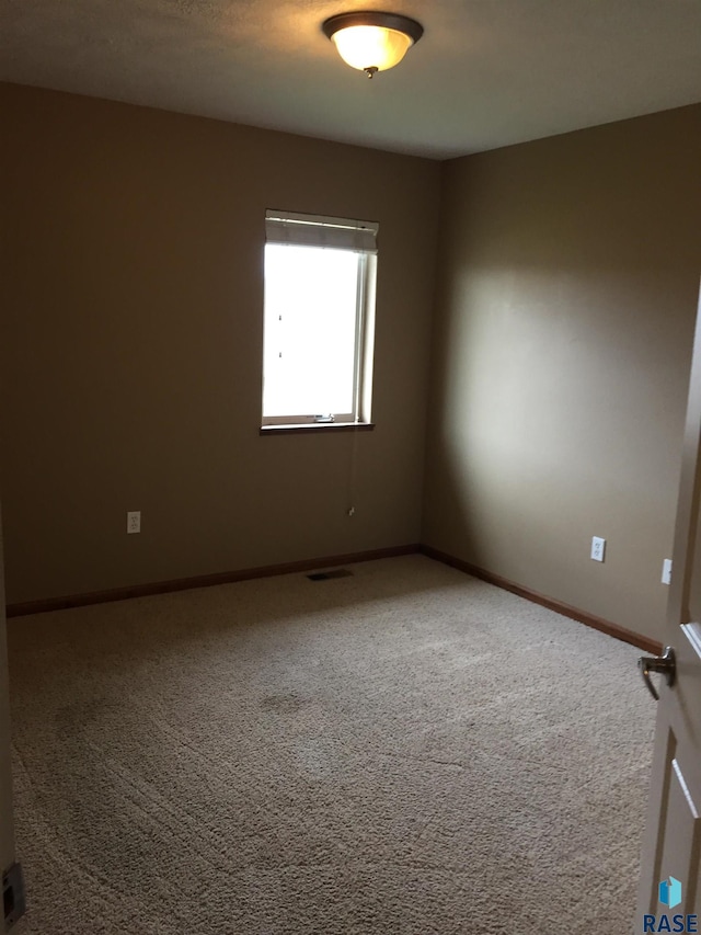 unfurnished room with visible vents, carpet, and baseboards