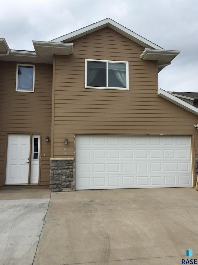 view of front of property featuring stone siding, driveway, and an attached garage