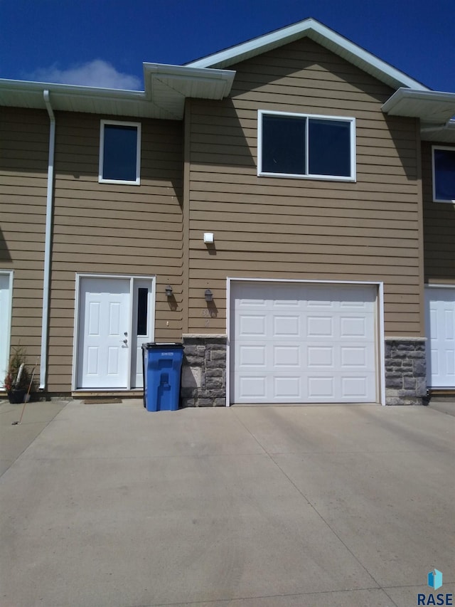 view of front facade featuring an attached garage, stone siding, and driveway