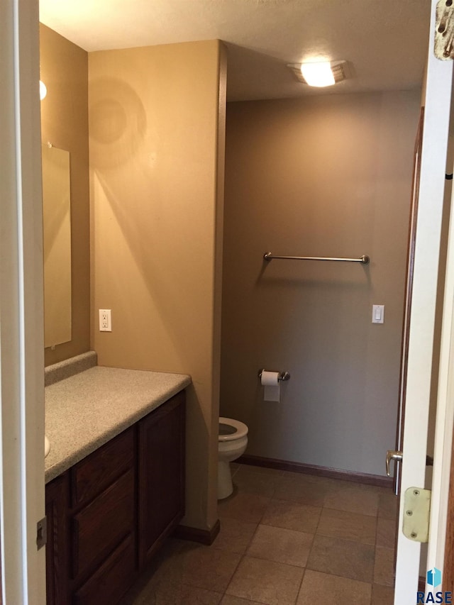 bathroom featuring tile patterned floors, baseboards, toilet, and vanity