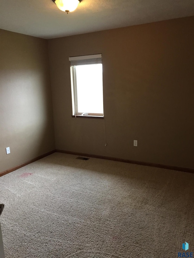 empty room featuring baseboards, visible vents, and carpet floors